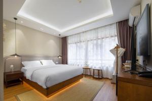 a bedroom with a large white bed and a window at Return to Emei Hotel in Baoguosi