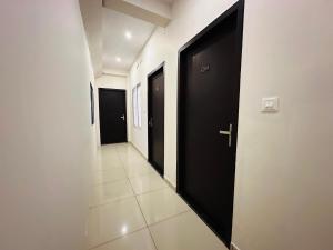 エルナクラムにあるEmar suites and roomsの黒いドア2つとタイルフロアの廊下 +2枚の写真
