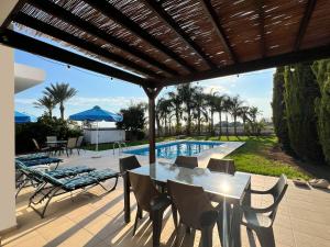 a patio with a table and chairs and a pool at Villa Aris in Ayios Theodhoros