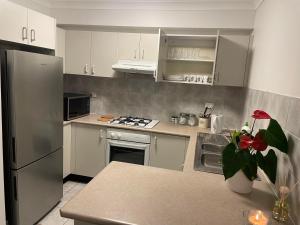 a kitchen with white cabinets and a stainless steel refrigerator at Sai House in Blacktown