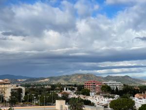 a city under a cloudy sky with mountains in the background at AGH Canet in Canet de Berenguer