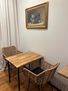 a wooden table with two chairs and a painting on the wall at Apartamenty Warszawska in Toruń