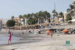 un grupo de personas en una playa con sombrillas en Casa en Playa de Arinaga, en Arinaga