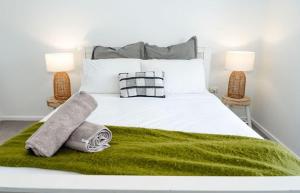 1 cama blanca con manta verde y 2 lámparas en Salt bush cottage Peterborough, en Peterborough