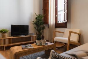 Una sala de estar con un televisor y una mesa. en tuGuest Bib Rambla Aparments, en Granada