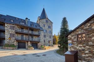 ein großes Steingebäude mit einem Turm auf einer Straße in der Unterkunft Pleta Baqueira Luxe 10 by FeelFree Rentals in Naut Aran