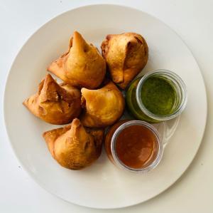 a plate of food on a plate with dipping sauce at Nath Homestay in Ujjain
