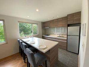 eine Küche mit einer großen Insel mit Stühlen und einem Kühlschrank in der Unterkunft Mopow Niseko in Niseko