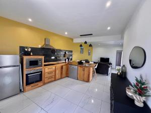 a kitchen with wooden cabinets and a stainless steel refrigerator at Villa Charpentier in Sainte-Marie