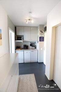 a kitchen with white cabinets and a white counter top at 49 Ferienwohnung NEU am Südstrand Fehmarn 4U App.64-212 in Burgtiefe auf Fehmarn  +10 photos