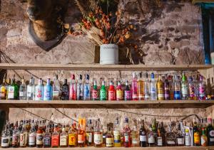 a shelf filled with lots of different types of alcohol at Lyde Court Country House in Hereford