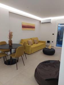 een woonkamer met een gele bank en een tafel bij Resort Beach Living in Lagonisi in Kalívia Thorikoú +1 foto