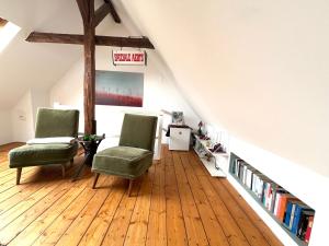 a room with two chairs and books on a wooden floor at Helles Giebelzimmer im Altbau in Cologne