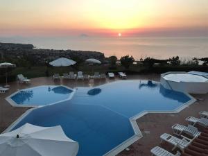 a large pool with chairs and umbrellas at sunset at Marasusa Apartments Scirocco 226CW in Parghelia