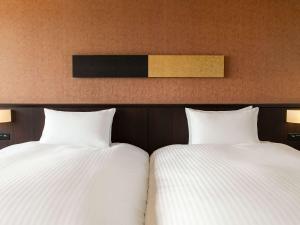 two beds sitting next to each other in a bedroom at Grand Mercure Okinawa Cape Zanpa Resort in Yomitan