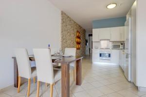 a kitchen and dining room with a wooden table and white chairs at Modern 2BR Sliema Apartment in Sliema