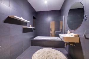 a bathroom with a sink and a tub and a mirror at Modern 2BR Sliema Apartment in Sliema