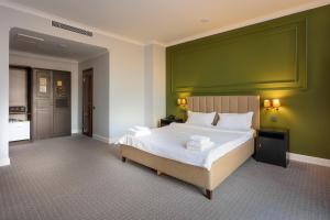 a bedroom with a large bed with a green wall at GRAND OPERA HOTEL in Almaty