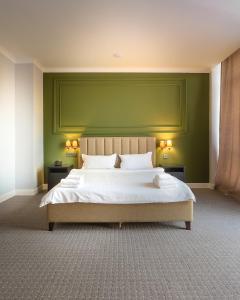 a bedroom with a large bed with a green wall at GRAND OPERA HOTEL in Almaty