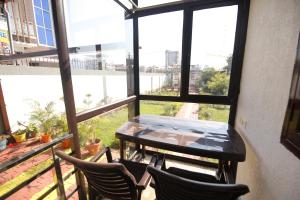 a balcony with a table and chairs and windows at Aditya Cottage in Rishīkesh
