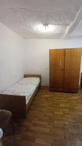 een slaapkamer met een bed en een houten kast bij Run İn Joy Hostel in Qostanaj