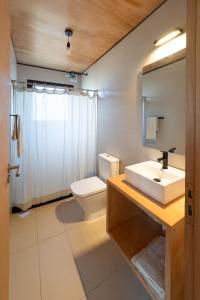 a bathroom with a sink and a toilet and a mirror at Refugios Pura vida in La Paloma