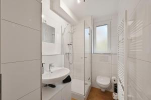 Un baño blanco con lavabo e inodoro. en SANO - Bei Holger in Hagen - Ruhige Lage - Stylisch - Waschmaschine - Platz zum Arbeiten, en Hagen 7 fotos más