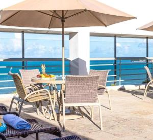 a table and chairs with an umbrella on a balcony at HOTEL TAMBAÚ FLAT EXCLUSIVE apt particular in João Pessoa