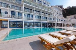 a large hotel with a swimming pool and lounge chairs at Alimuri Bay Resort in Meta +81 photos