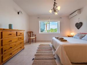 a bedroom with a bed and a dresser and a window at Villa Can Petrus, con piscina y wifi gratis in San Antonio Bay +32 photos
