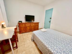 アリカンテにあるGardela Rooms Mercadoのベッドとドレッサーの上にテレビがある寝室