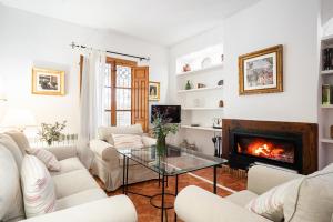 a living room with white furniture and a fireplace at Casa rural Buenos Días con piscina, barbaco y chimenea in Padul
