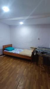 een slaapkamer met een bed en een houten vloer bij Run İn Joy Hostel in Qostanaj
