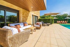 a patio with wicker furniture next to a pool at Villa California - Costa Brava - Platja d'Aro in el Mas Vila +38 photos