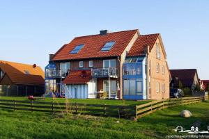 a house with a red roof on a green field at 20 Ferienwohnung im Fritz-Bleyl-Weg 16a OG in Burg auf Fehmarn