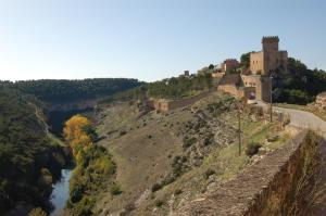 un castillo en la cima de una colina junto a un río en La Posada del Hidalgo de Alarcón, en Alarcón