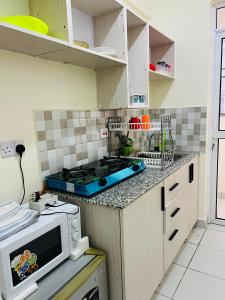 une cuisine avec une cuisinière et un micro-ondes dans l'établissement Uniplex Homes 2 bedroom with 2 beds, à Mombasa