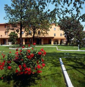 ein großes Gebäude mit roten Rosen im Hof in der Unterkunft Hotel Dall'Ongaro in Ghirano
