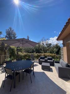 a patio with a table and chairs and an umbrella at Maison jasmin Porto Vecchio in Porto-Vecchio