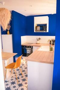 - une cuisine avec des murs bleus, une table et un évier dans l'établissement Studio Majorelle, à Sotteville-lès-Rouen