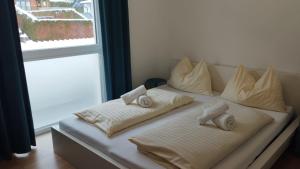 a bed with three pillows on it next to a window at Apartment Bergblick by Alpenidyll Apartments in Weißenbach