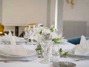 a table with white plates and glasses and flowers at Logis Le Clos Deauville Saint Gatien in Saint-Gâtien-des-Bois +55 photos