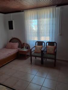 a bedroom with two chairs and a bed and a window at Maria's Home in Kakóvatos