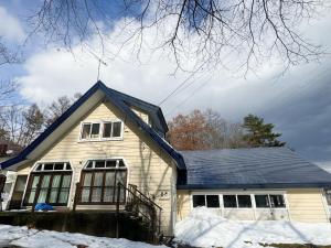 a house with a blue roof in the snow at Amigo guest house in Hakuba