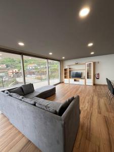 ein großes Wohnzimmer mit einer Couch und einem großen Fenster in der Unterkunft Sunset Valley House in Ribeira Brava