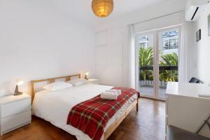 a white bedroom with a bed and a window at Spacious Apartment T3 Near Beach in Estoril