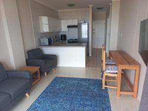 a living room with a couch and a table and a kitchen at 215 Sea View in Cape Town