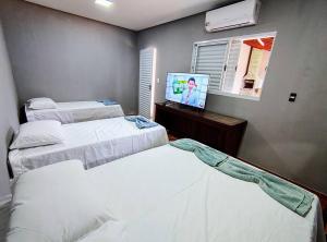 大坎普moradadigiorgio edicula com piscina的一间卧室，里面有两张床和一台电视