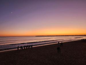 a group of people walking on the beach at sunset at Le Capitole - Studio d'exception accès direct à la plage Benoît in La Baule
