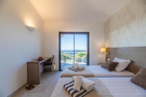 a bedroom with two beds and a desk and a window at Résidence Les Terrasses de Rondinara in Bonifacio